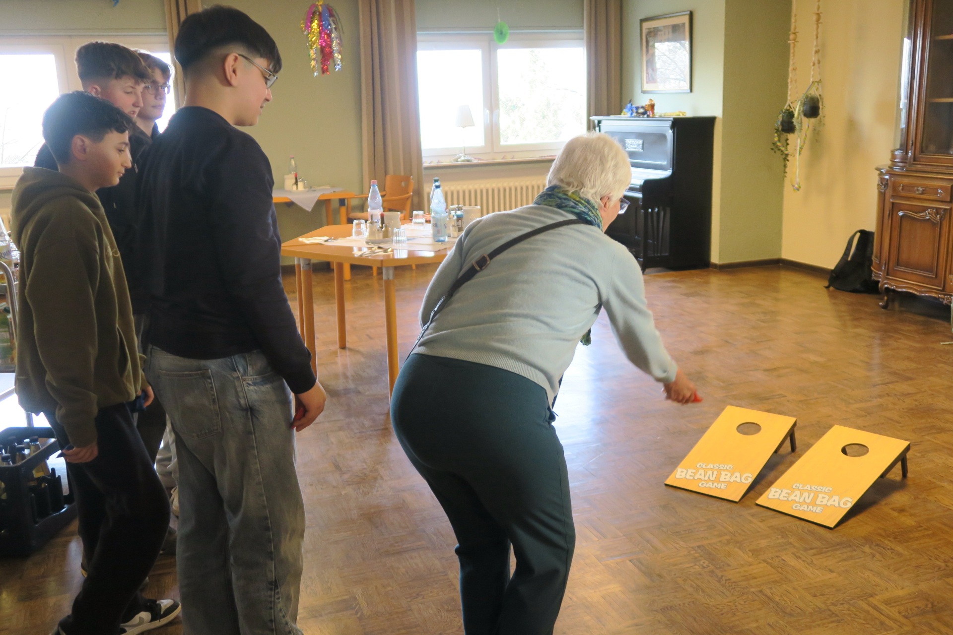 Schüler schauen einer Seniorin beim Spielen zu